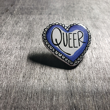Load image into Gallery viewer, The pin is heart shaped and says the word "Queer" in the center. The color is blue