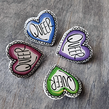 Load image into Gallery viewer, Each pin is heart shaped and says the word "Queer" in the center. They come in blue, purple, pink and green.